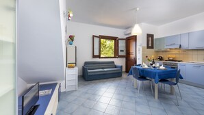 A compact living space with a sofa, dining table, and kitchenette. - I tre Golfi Paprica (San Vito Lo Capo)