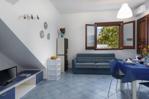 A compact living space with a sofa, dining table, and a television.