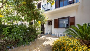A courtyard with a tiled floor, a white chair, and yellow flowers. - I tre Golfi Paprica (San Vito Lo Capo)