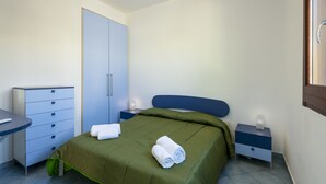 A bedroom with a bed, a dresser, a nightstand, and a wardrobe. - I tre Golfi Paprica (San Vito Lo Capo)