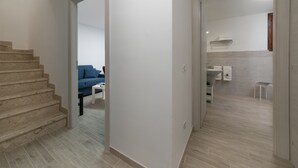 A modern apartment with a staircase, a living area with a blue sofa, and a kitchen with a sink and countertop.