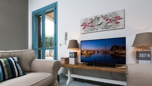 Un salon avec un canapé, un téléviseur posé sur un meuble en bois, une lampe et un tableau accroché au mur.