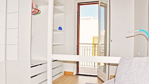 Une pièce avec une armoire blanche, un canapé gris et un balcon avec vue.
