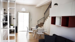 Un salon moderne avec un escalier, un coin repas et des étagères intégrées.