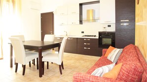 Una cocina moderna con una mesa de comedor y sillas, un sofá y un horno empotrado.