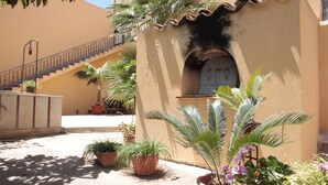 Un patio con escaleras, plantas en macetas y un edificio con techo de tejas.
