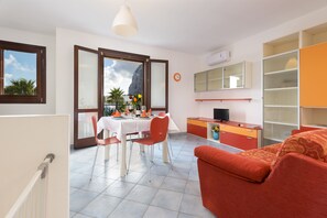 A modern apartment with a dining area, a sofa, a TV, and a view of the mountains. - I tre Golfi Zenzero (San Vito Lo Capo)