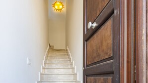 A staircase leading to a room with a wooden door and a light fixture at the top. - I tre Golfi Zenzero (San Vito Lo Capo)