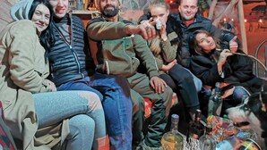 A group of people sitting on a couch in a room with stone walls and a rustic interior.