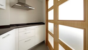 A modern kitchen with white cabinets, a black countertop, and a stainless steel range hood. - Muinoa 1 by FeelFreeRentals (Donostia)