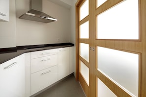 A modern kitchen with white cabinets, a black countertop, and a stainless steel range hood.