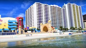 A beachfront hotel with multiple high-rise buildings, a prominent archway, and a sandy beach.