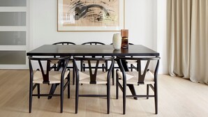 A dining area with a rectangular table, six chairs, a framed abstract painting, and a vase with a candle. - Enbata by FeelFreeRentals (San Sebastian)