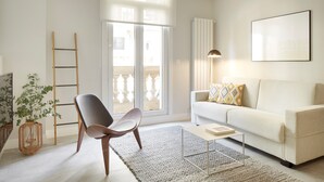 A modern living room with a sofa, a chair, a coffee table, a lamp, and a large window. - Príncipe by FeelFreeRentals (Donostia)