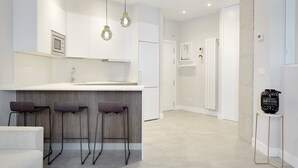 A modern kitchen with a central island, bar stools, and pendant lighting. - Príncipe by FeelFreeRentals (Donostia)