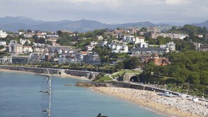 Eine Küstenstadtlandschaft mit Strand, Gebäuden und Bergen im Hintergrund.