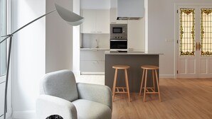 Une cuisine moderne équipée d’un four à micro-ondes, d’un four traditionnel et d’un petit îlot central avec des tabourets.