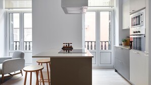 Une cuisine moderne dotée d’un îlot central, de tabourets de bar et d’un coin repas avec une chaise.