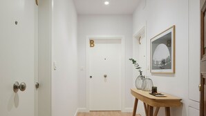 A hallway with a wooden floor, white walls, and doors marked with letters A and B. - Mayor Suite 3 by FeelFree Rentals (San Sebastián)