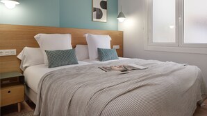 A neatly made bed with a striped blanket, a wooden headboard, and two bedside tables with lamps. - Mayor Suite 3 by FeelFree Rentals (San Sebastián)