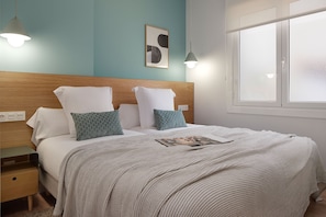 A neatly made bed with a striped blanket, a wooden headboard, and two bedside tables with lamps.