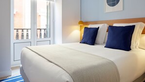 A hotel room with a large bed, a headboard, a wall-mounted lamp, and a window with a view of buildings. - Mayor Suite 3 by FeelFree Rentals (San Sebastián)
