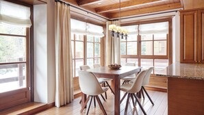 Un coin repas avec une table en bois, des chaises blanches et un lustre.
