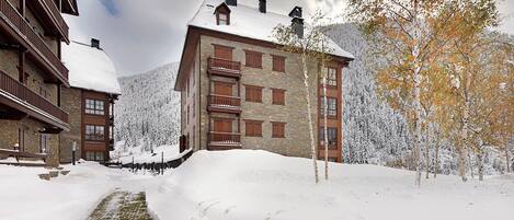 A snow-covered building with a stone facade and wooden balconies.