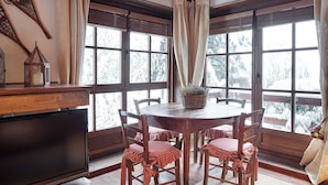 A cozy dining area with a wooden table and chairs, a television, and large windows with curtains. - Val de Ruda Luxe 65 by FeelFree Rentals (Baqueira)