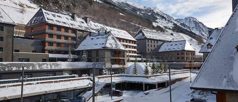 A hotel with multiple buildings, snow-covered roofs, and a mountainous backdrop.