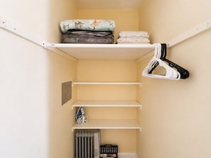 A storage closet with shelves, a radiator, and hanging storage. - Cozy Gulfport Studio with King Bed + Full Kitchen walkable to Beach Blvd (Gulfport)