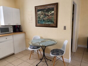 Une cuisine compacte équipée d’un four à micro-ondes, d’une machine à café et d’une table à manger avec des chaises.