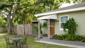 A house with a porch, a small table with chairs, and a wooden fence. - Cozy Gulfport Studio with King Bed + Full Kitchen walkable to Beach Blvd (Gulfport)