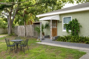 A house with a porch, a small table with chairs, and a wooden fence. - Cozy Gulfport Studio with King Bed + Full Kitchen walkable to Beach Blvd (Gulfport)