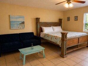 Une chambre à coucher avec un lit, un canapé, une petite table et un ventilateur de plafond.