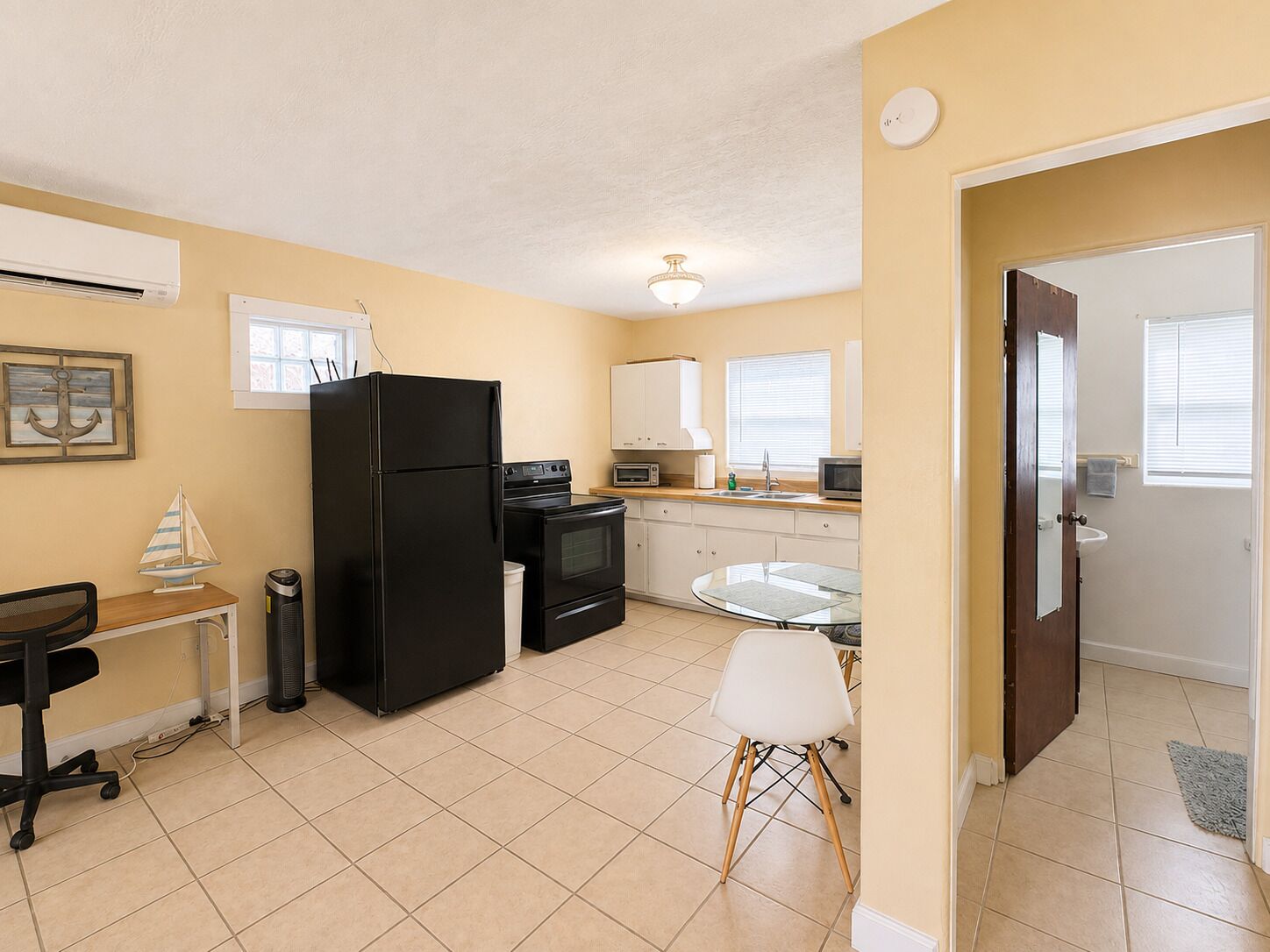 A compact kitchen with a refrigerator, stove, microwave, and a small dining table with chairs.