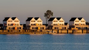 Een pand aan het water met meerdere huizen, elk voorzien van een balkon en een garage.