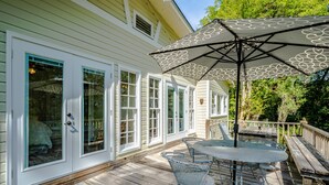 Une terrasse couverte avec une table et des chaises, un grand parasol et une clôture en bois.