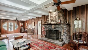 Un salon spacieux avec une cheminée en pierre, des murs en bois et une grande fenêtre.