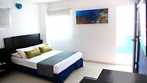 Ein Hotelzimmer mit Bett, Nachttisch, einem Bild an der Wand und einem Fenster mit Blick.