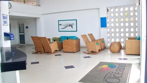 Eine Lobby mit Korbmöbeln, einer Fußmatte und einem Wandbild einer Meeresschildkröte.