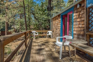 A wooden deck with a table and chairs, surrounded by trees. - L'Auberge Des Oiseaux Chantants (Willeman)