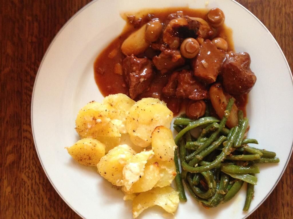 Un plato con estofado de carne, patatas hervidas y judías verdes.