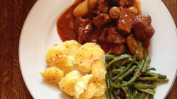 Un plato con estofado de carne, patatas hervidas y judías verdes.