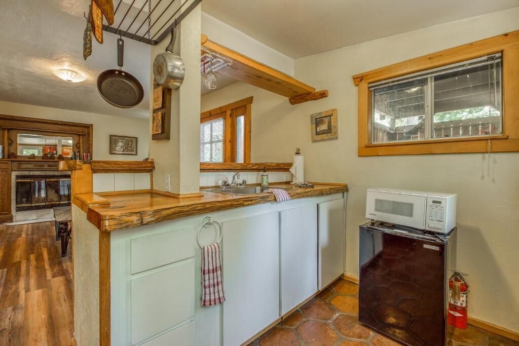 A kitchen with a wooden countertop, white cabinets, a microwave, and a fire extinguisher.