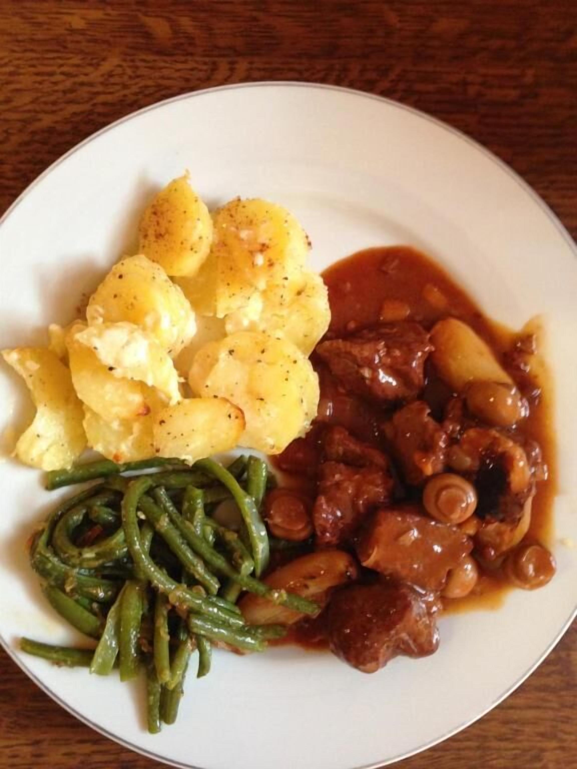 A plate with mashed potatoes, green beans, and a meat dish with beans.