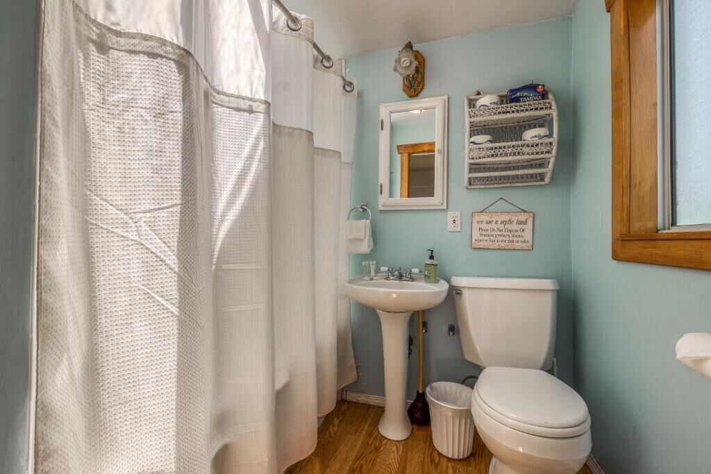 Een badkamer met een wit wastafel, toilet, douchegordijn en spiegel.