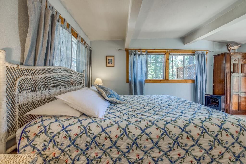 A bedroom with a bed, a nightstand, a lamp, and a window with curtains.