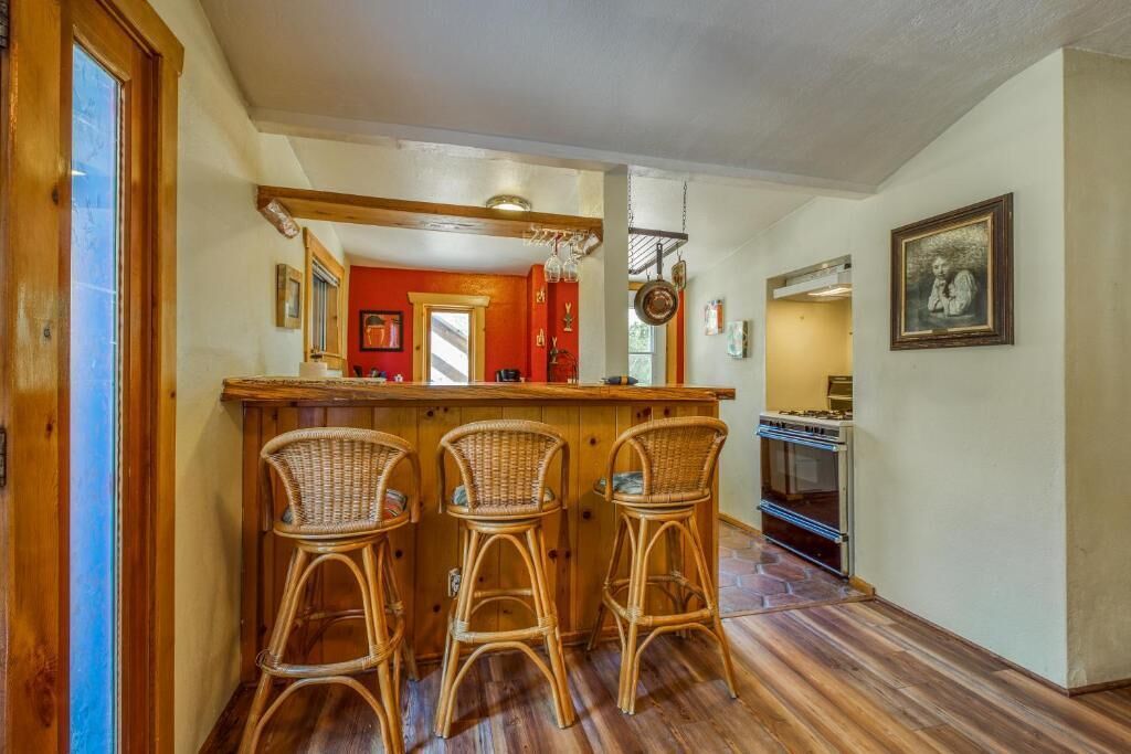 A kitchen with a wooden bar and three wicker chairs.