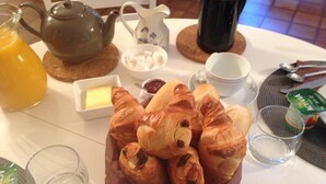 A breakfast setting with croissants, butter, jam, and a teapot on a table. - L'Auberge Des Oiseaux Chantants (Willeman)